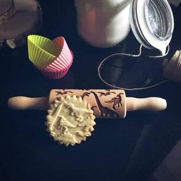 Dinosaurs pattern on a small wooden embossed rolling pin for children, with the cookies it prints
