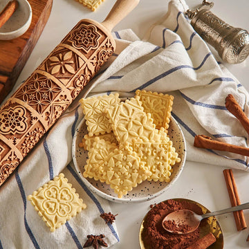 Vintage pattern engraved on a wooden embossed rolling pin, beside the shortbread cookies it prints