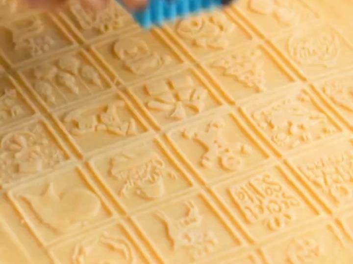 Hands rolling a Pastrymade embossed rolling pin over cookie dough